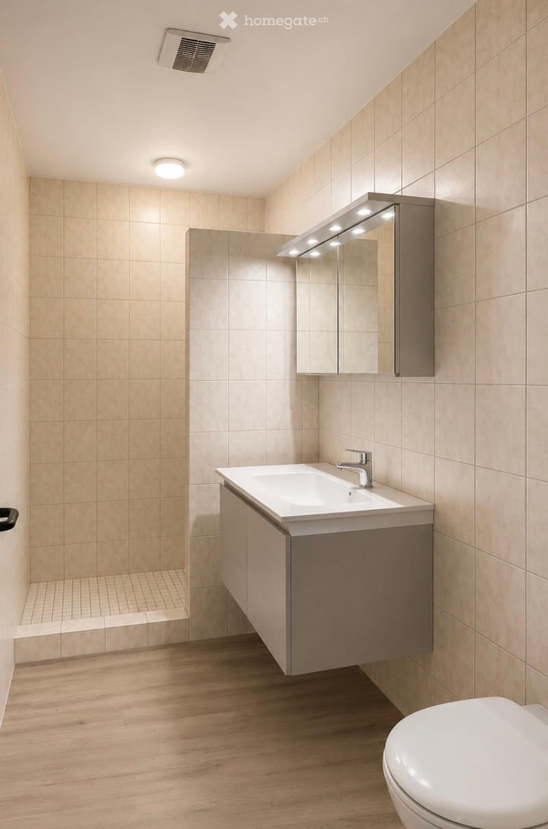 Modern bathroom with beige tiled walls, wooden flooring, a white sink with a chrome faucet, a mirrored cabinet with built-in lighting, and a toilet.