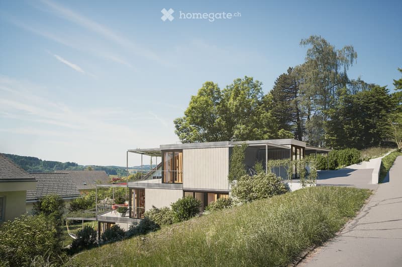 Modern, raised house with a flat roof and large windows, surrounded by greenery and trees.