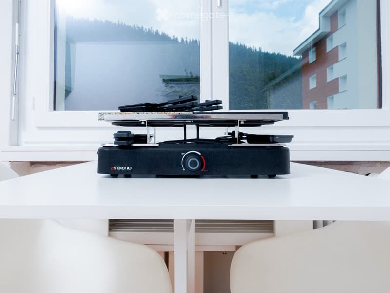 Modern kitchen with an electric griller on a white table with a scenic view outside