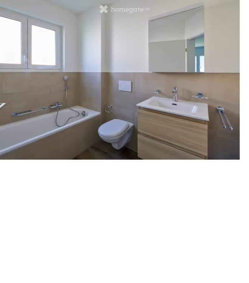 Modern bathroom with a bathtub, toilet, sink, and mirror. Features a wooden vanity with a double sink and a large mirror above it. The walls are painted in a light neutral color with a beige accent on the lower half.