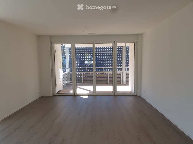 Empty room with wooden flooring and large sliding glass doors leading to a balcony area.