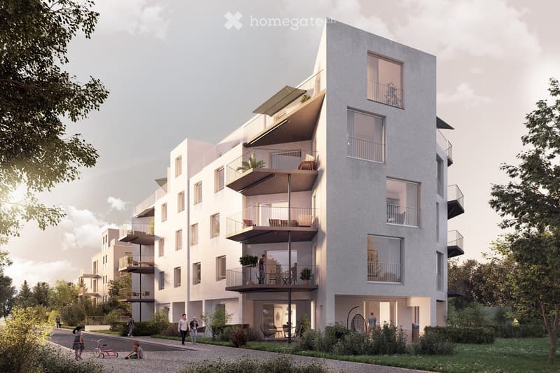 Modern multi-story residential building with balconies, large windows, and contemporary design. The building features a mix of light-colored facades and glass elements, surrounded by greenery and a paved walkway.