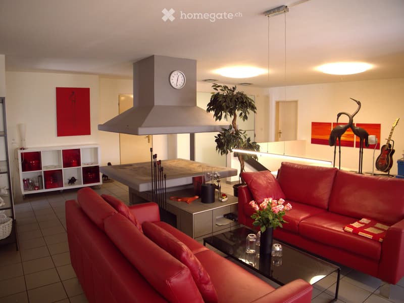 Modern living room with red leather sofa, glass coffee table, flower vase, clock, shelf, guitar, and decorative art pieces.