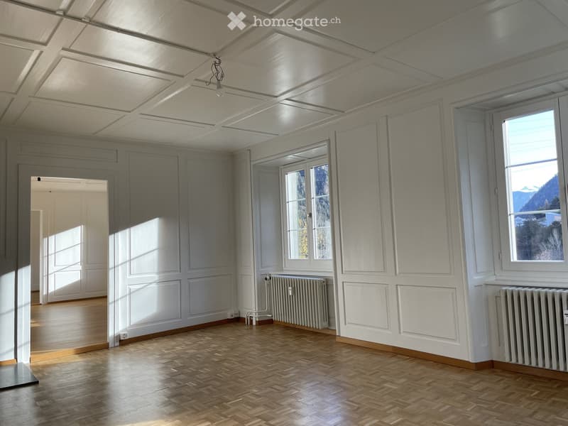 Empty room with wooden flooring, white walls, large windows, and radiators. No furniture or equipment present.
