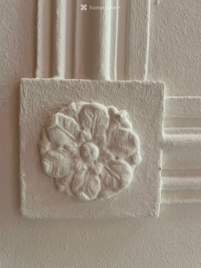 Close-up of a decorative stone plaque with a stylized flower design mounted on a brick wall.
