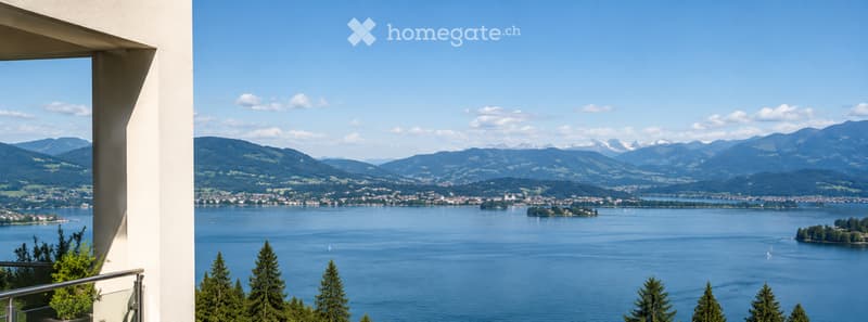 Balcony overlooking a scenic lake with distant mountains and a town in the background.