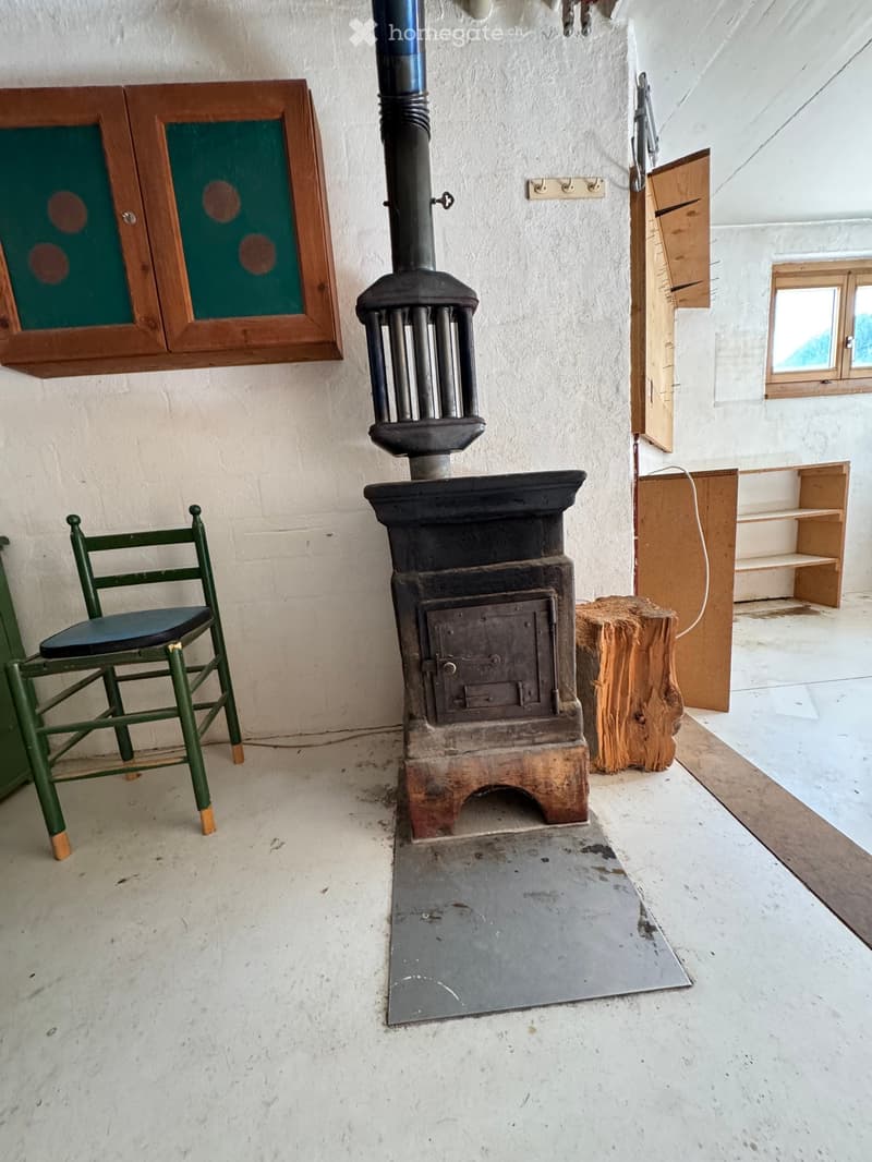 Room with a wood-burning stove, a wooden chair, a wooden cabinet, and a wooden shelf.