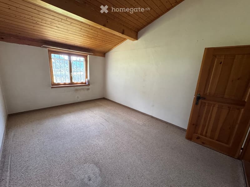 Empty room with wooden door, window with metal bars, and carpeted floor.
