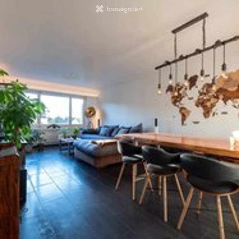 Modern living room with dark wooden flooring, a large sofa, coffee table, pendant lights, and a dining area with chairs and a table.