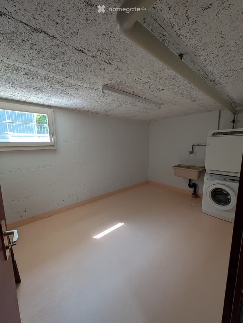 Empty room with white walls, a small window, a washing machine, and a sink.