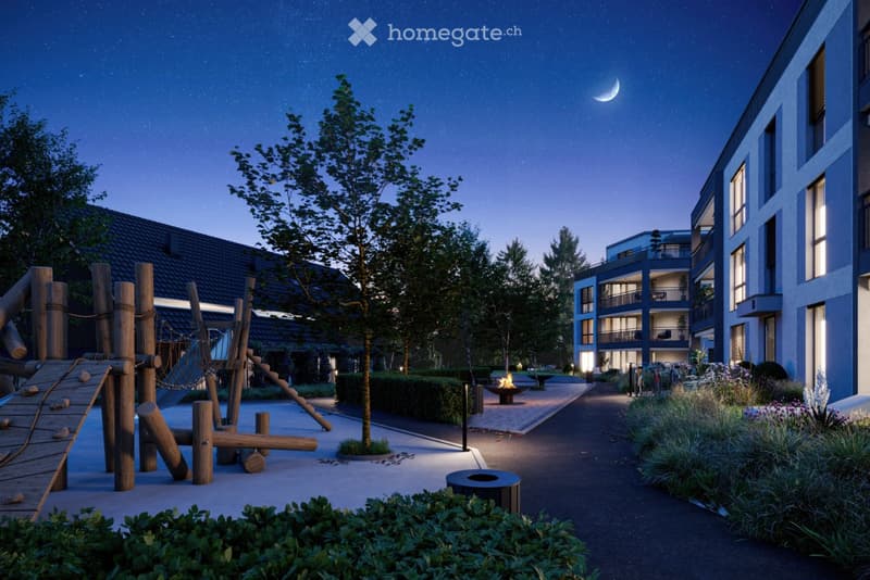 Nighttime view of a residential complex with modern apartment buildings, a playground, trees, and a pathway.