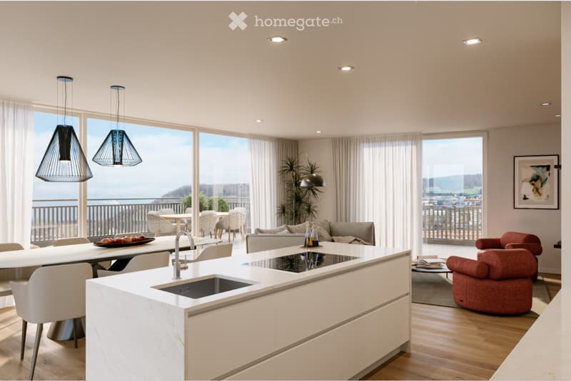 Modern open-plan living and dining area with a sleek white kitchen island, pendant lights, large windows offering a scenic view, and comfortable seating including a sofa and chairs.