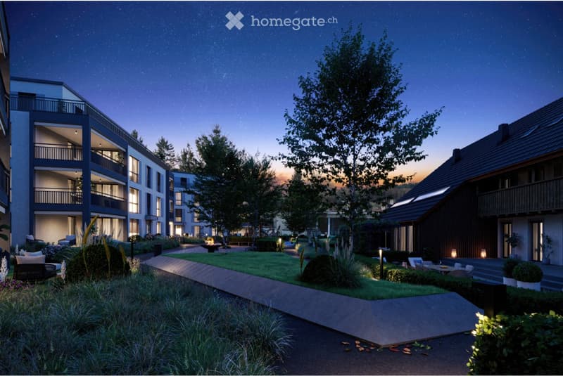 Nighttime view of a modern residential complex with multiple buildings, balconies, and landscaped gardens.