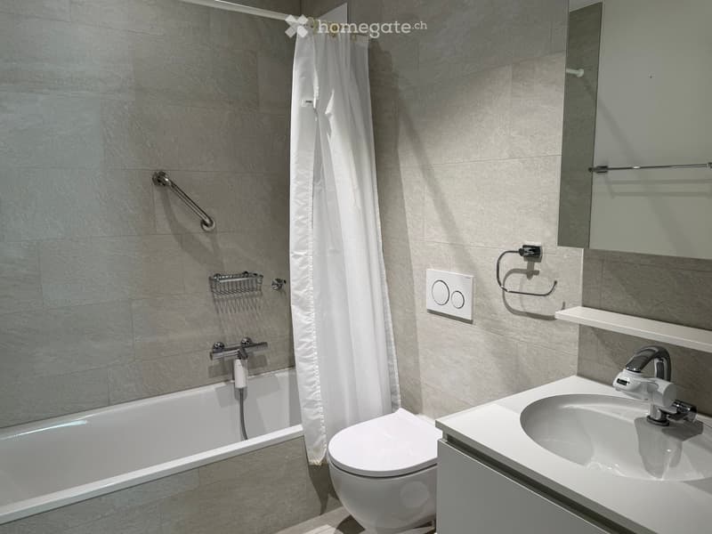 Modern bathroom with a bathtub, toilet, sink, mirror, and shower curtain. Features a towel rack and a modern faucet.