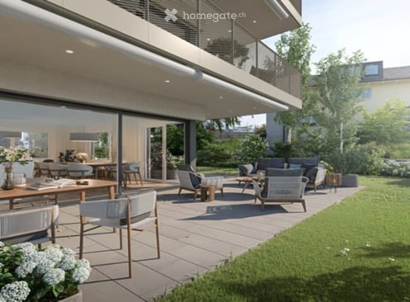 Modern outdoor patio area with wooden furniture, including tables and chairs, connected to a multi-story house with large glass windows and a balcony.