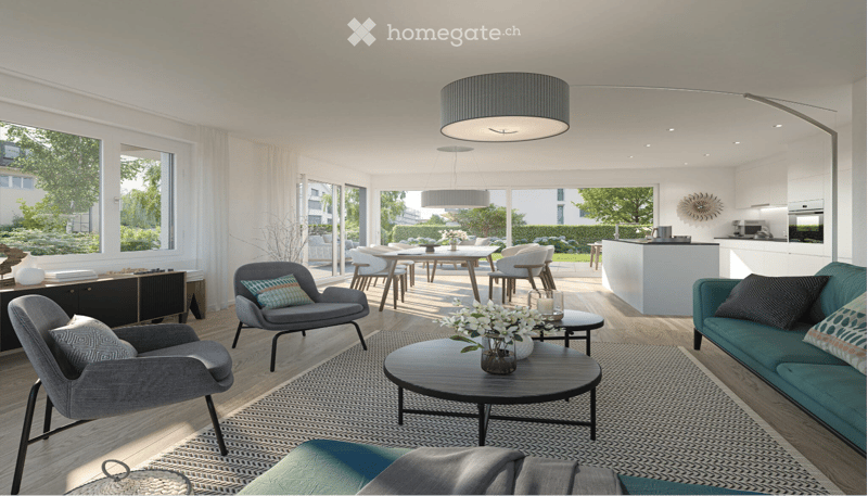 Modern living room with a grey sofa, coffee table, armchairs, and a dining area with a table and chairs. The space features large windows with white curtains, a patterned rug, and a kitchen area visible in the background.