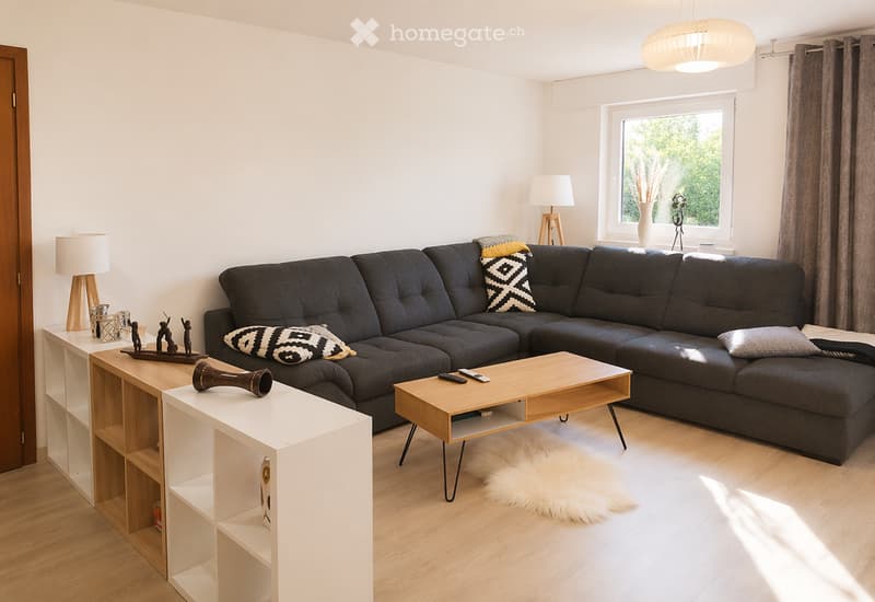 Modern living room with a dark grey sectional sofa, wooden coffee table, side table, floor lamp, and decorative items on shelves.