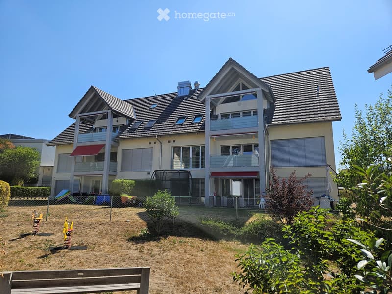 Two-story house with a modern design, featuring multiple balconies, large windows, and a fenced yard with a trampoline and playground equipment.