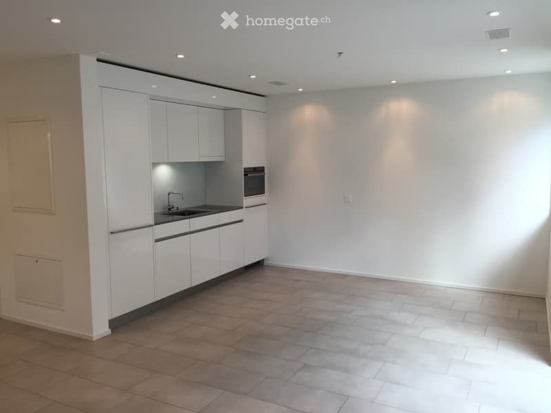 Modern kitchen with white cabinets, a sink, and an oven, featuring a tiled floor and recessed lighting.