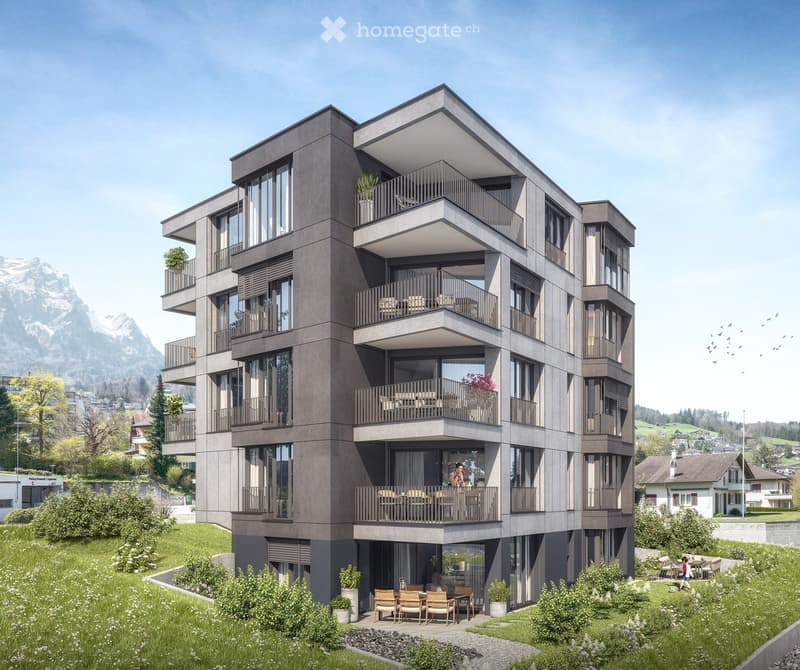 Modern multi-story residential building with balconies, large windows, and a scenic mountain view in the background.