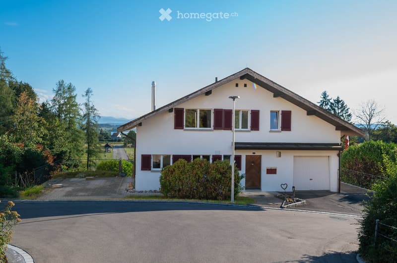 Two-story white house with red shutters, garage, and well-maintained garden.