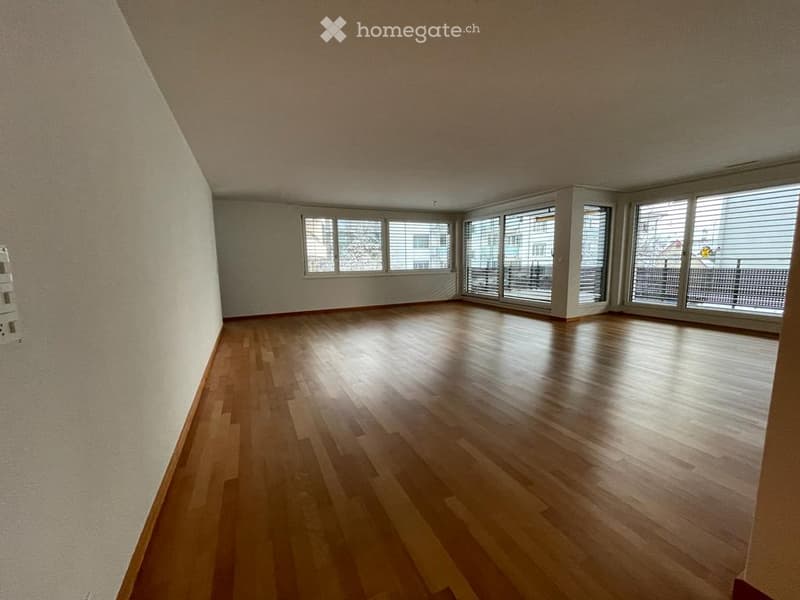Empty room with wooden flooring and large windows with blinds, no furniture or equipment.