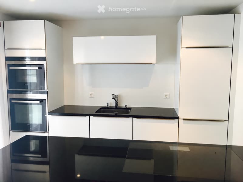 Modern kitchen with white cabinets, black countertops, stainless steel oven, and a sink with a modern faucet.
