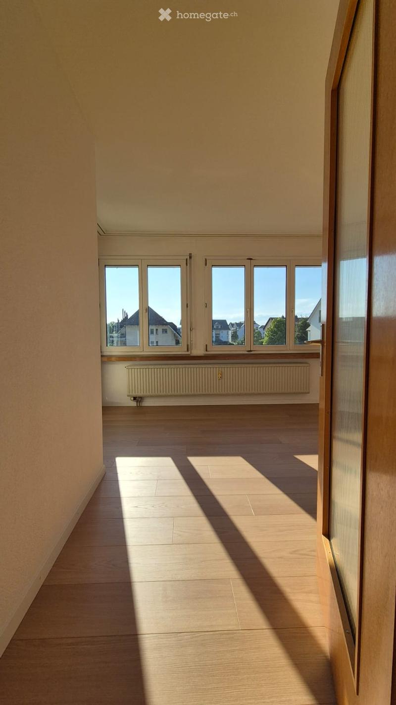 Empty room with wooden flooring, large windows, and a radiator. No furniture or equipment present.
