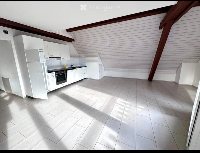 Bright, modern kitchen with white cabinets, stainless steel appliances, and tiled flooring. The space features a refrigerator, oven, and sink, with natural light streaming in from the slanted ceiling.