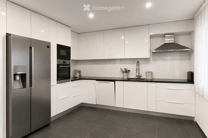 Modern kitchen with white cabinets, stainless steel appliances, and dark tiled flooring.