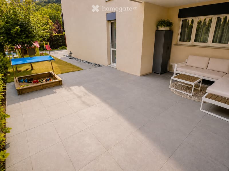 Balcony with tiled floor, white sofa, coffee table, cabinet, and a wooden toy box with toys.