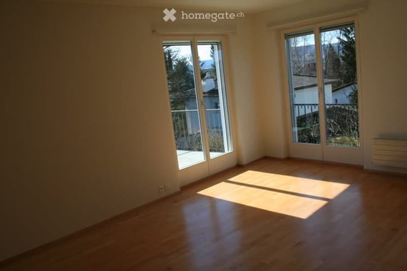 Empty room with wooden flooring, large windows, and natural light. No furniture or equipment present.
