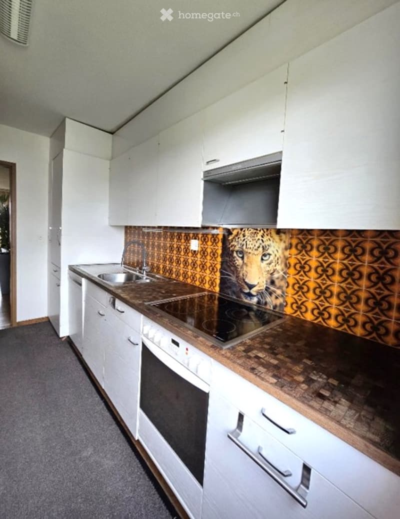 Modern kitchen with white cabinets, a wooden countertop, a sink, a stove, and an oven. The backsplash features a bold leopard print design.