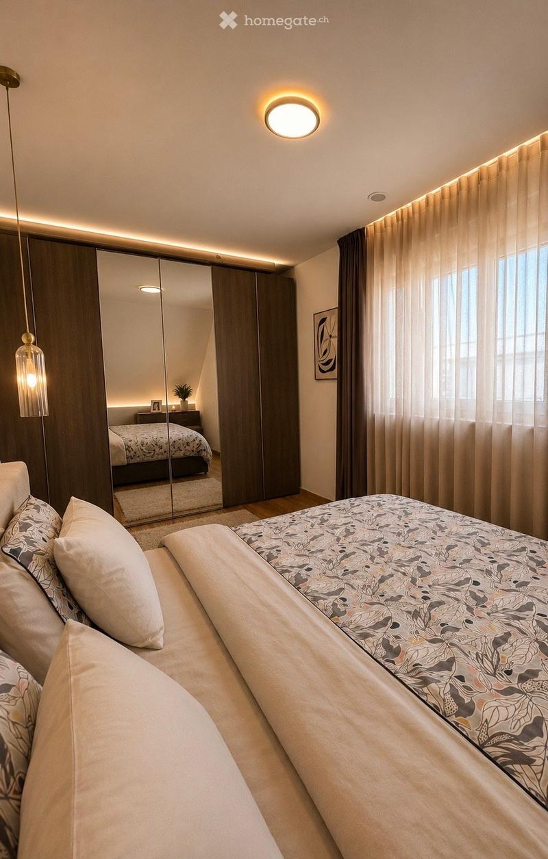 Modern bedroom with a large bed, decorative pillows, a mirrored wardrobe, pendant lighting, and a small plant on a nightstand.
