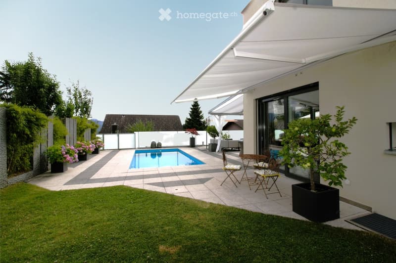 Well-maintained garden with a swimming pool, patio seating, and lush greenery.