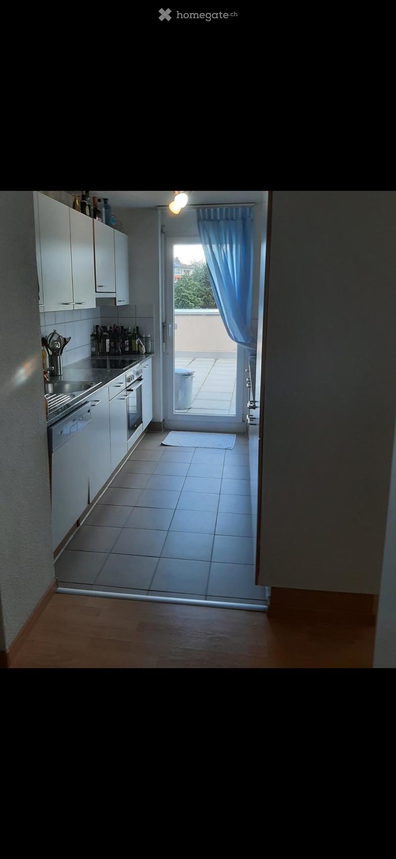 Modern kitchen with white cabinets, stainless steel appliances, and a sliding glass door leading to a balcony.