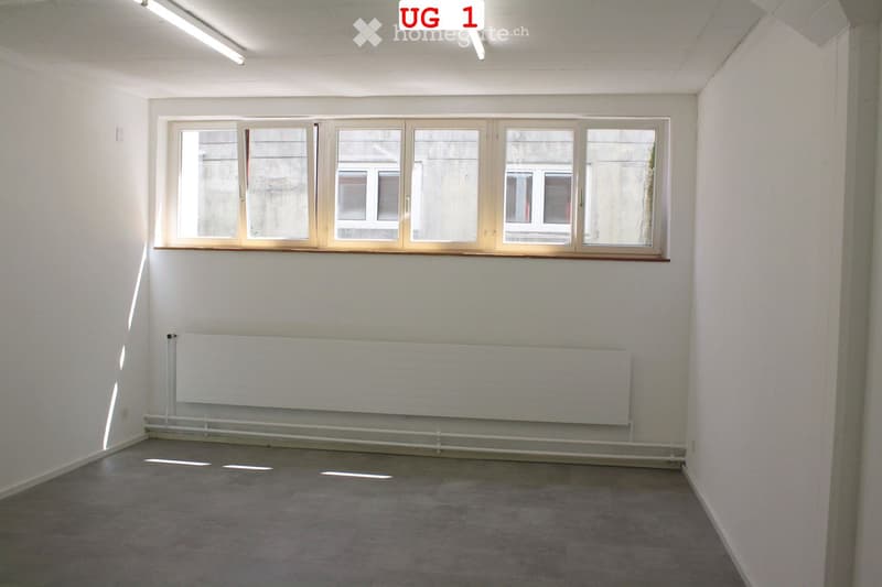 Empty room with white walls, concrete floor, large window with multiple panes, and a radiator below the window.
