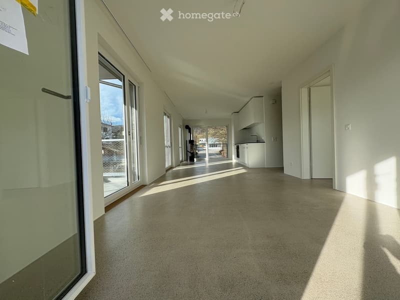 Empty room with light-colored walls, large windows, and a concrete floor. No furniture or equipment is present.