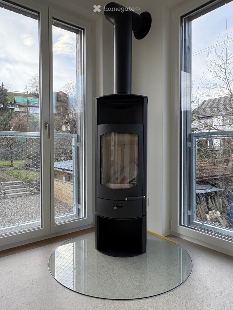 Modern room with a sleek black wood-burning stove and a round glass table.