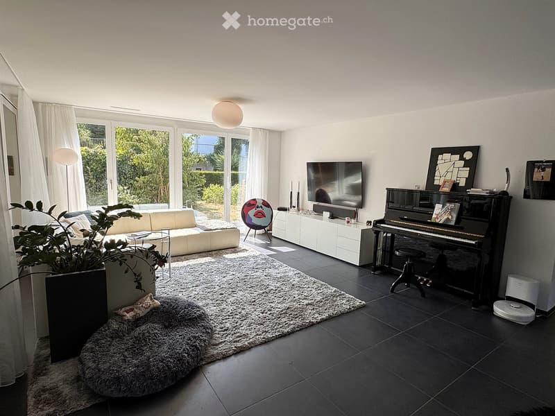 Modern living room with a white sofa, piano, television, and large windows with white curtains. Features a fluffy white rug, a large potted plant, and decorative artwork.