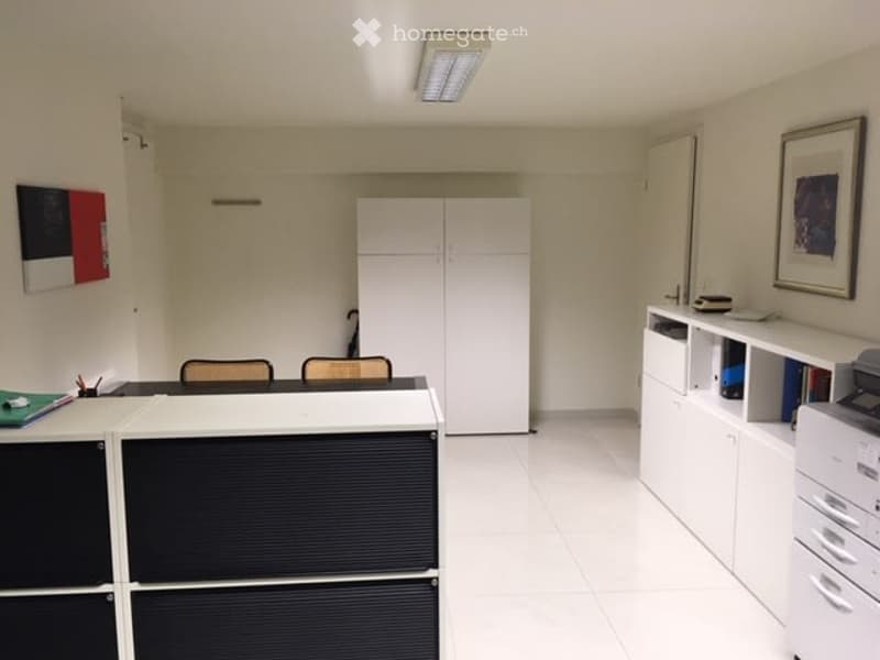 Office space with white tiled flooring, white walls, and modern furniture including a desk, chairs, cabinets, and a printer.