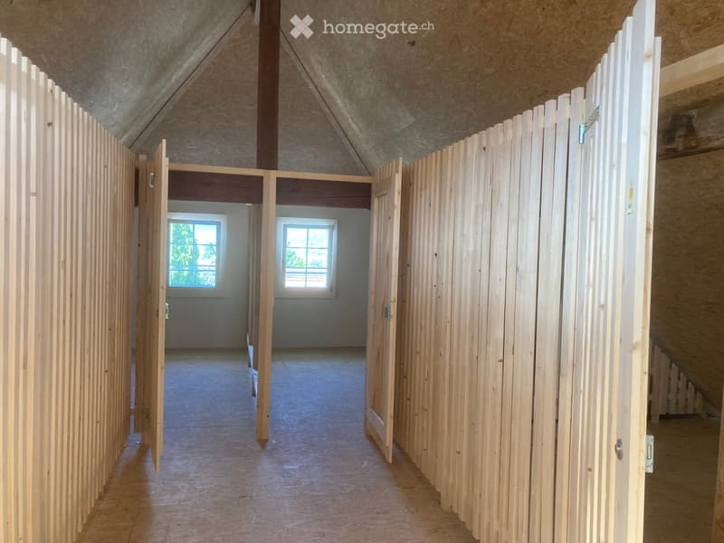 Empty hallway with wooden panel walls, open doors leading to rooms, and visible windows at the end.
