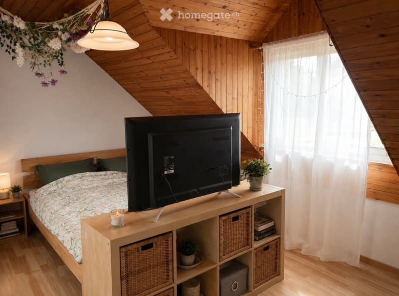 Cozy attic bedroom with wooden slanted ceilings, a large bed with a patterned duvet, a television on a wooden stand, and storage baskets.