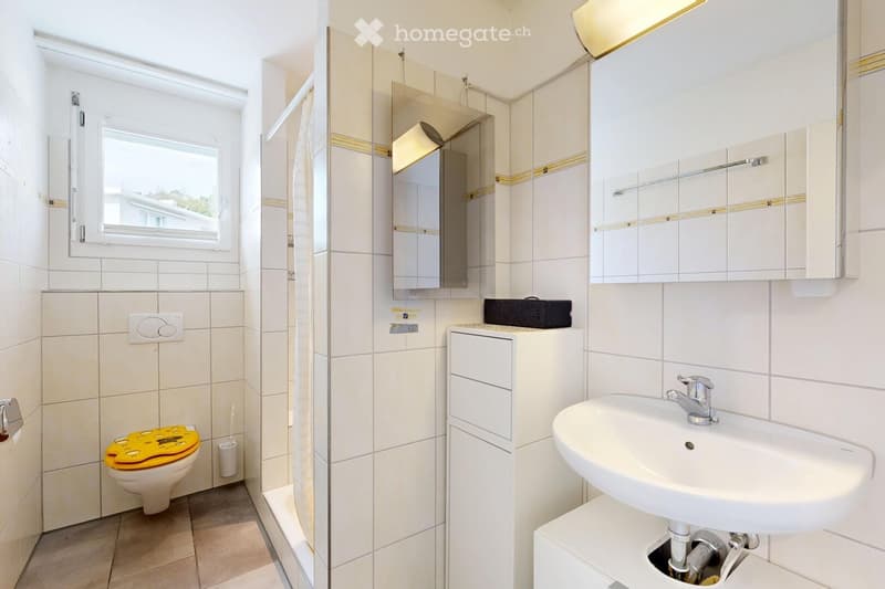 Modern bathroom with white tiles, a toilet with a yellow seat cover, a sink with a chrome faucet, mirrored cabinets, and a shower area.