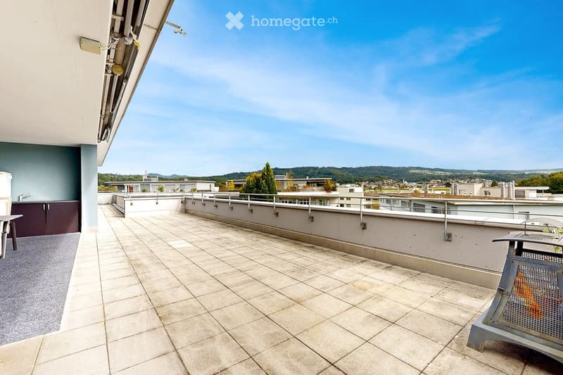 Roof terrace with tiled flooring, metal railing, and a view of the surrounding area and buildings.