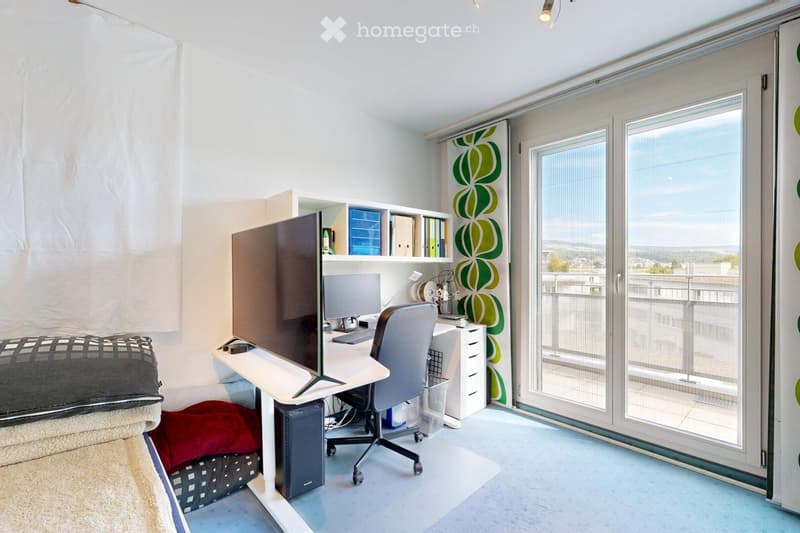 Modern, well-lit room with a desk setup, large window with a scenic view, and a comfortable bed area.