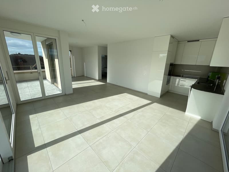 Empty kitchen with white cabinets, tiled floor, and large sliding glass doors leading to a balcony.