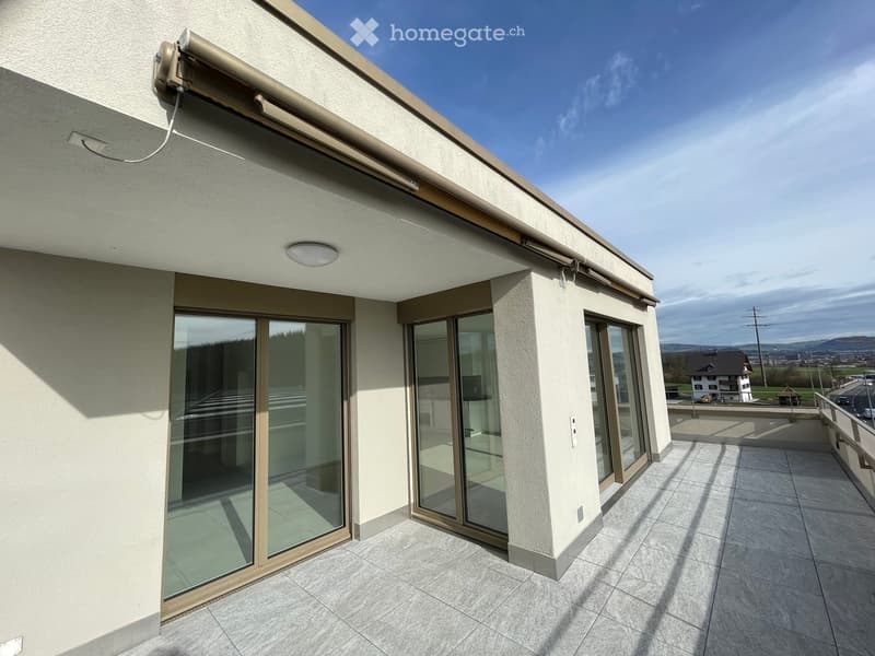 Balcony with large glass sliding doors, tiled floor, and a retractable awning on the roof.