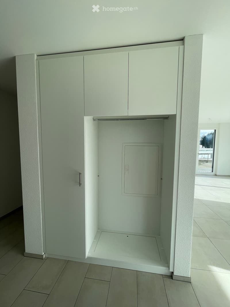 Empty closet space with white walls, tiled floor, and built-in cabinets with a sliding door.