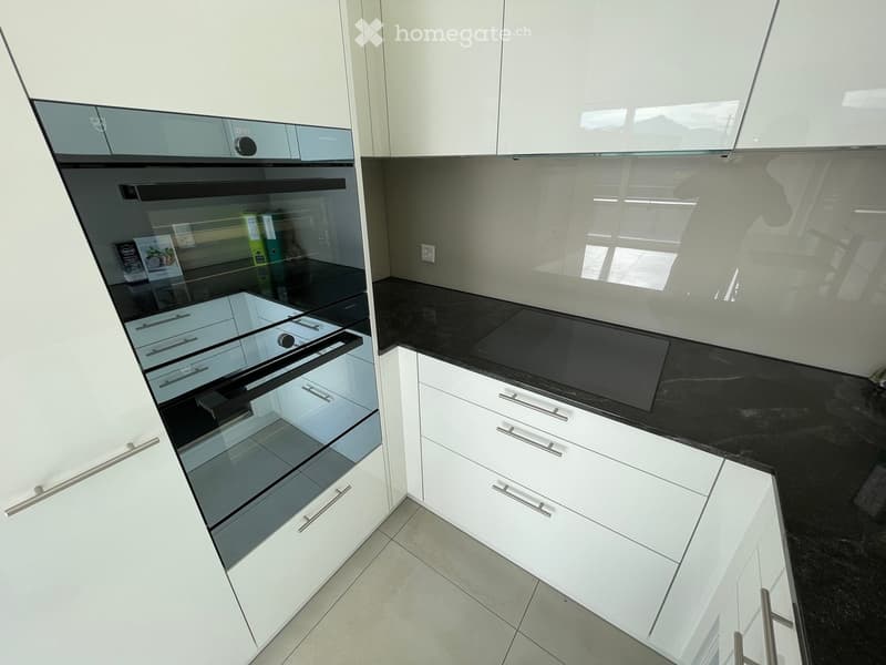Modern kitchen with white cabinets, black countertop, and built-in oven.